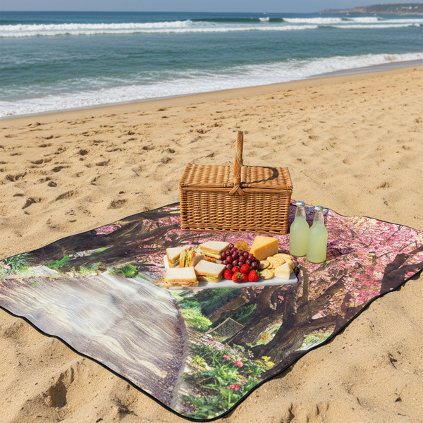 Picnic setup on a beach with a woven basket, food items, and a scenic blanket.